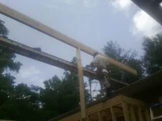 Carpenter setting a ridge beam over a new addition frame — Ice Dam Removal by Roofing Brothers in Swainsboro