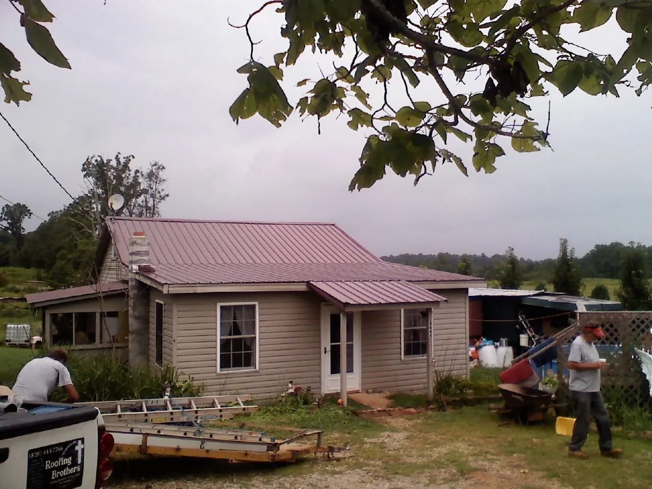Crew finishing a mauve metal roof on a small farmhouse in Swainsboro