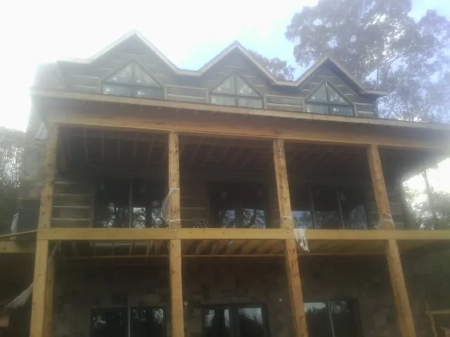 Dormers and porch framing on a large log home under construction — Roof Coating work by our crew in Swainsboro