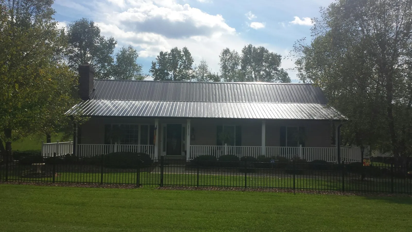 Gray metal roof on a brick ranch with a full width front porch — Gutter Guard Installation work by our crew in Swainsboro