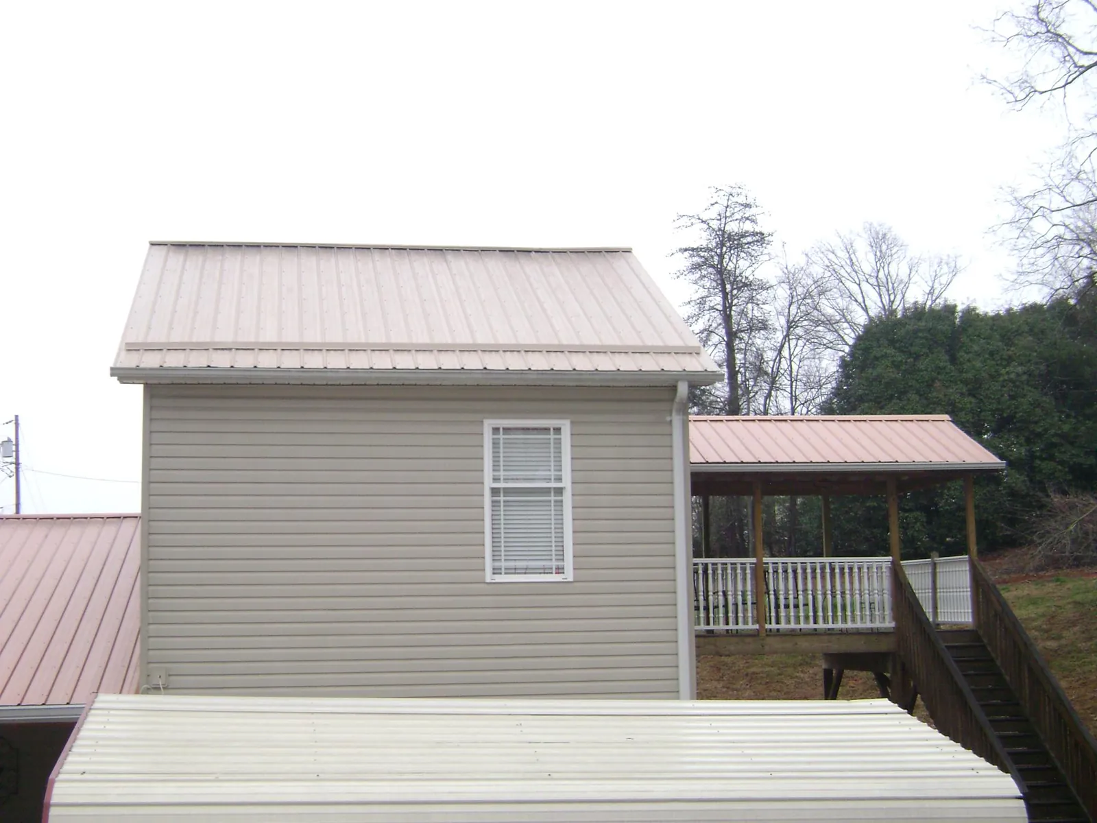 Tan metal roofs on a two story addition and attached porch, from a Roof Replacement job in Swainsboro
